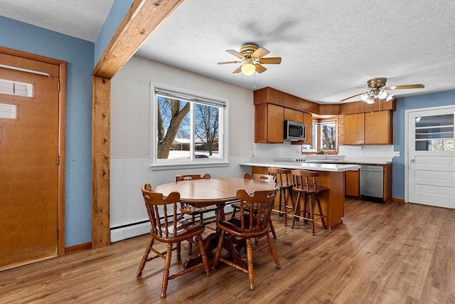 dining room featuring light wood-type flooring, a textured ceiling, visible vents, and a ceiling fan