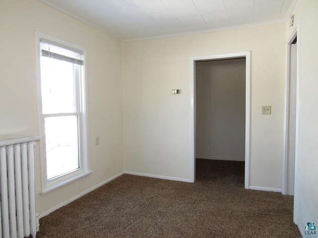 empty room featuring radiator, baseboards, dark carpet, and crown molding