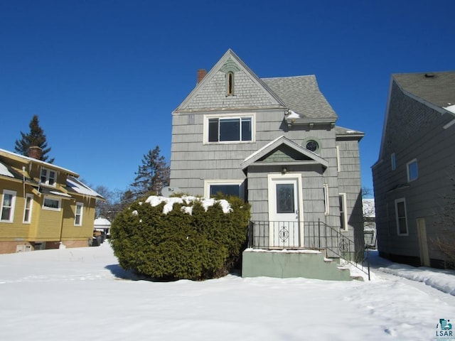 view of front of house featuring a shingled roof and a chimney