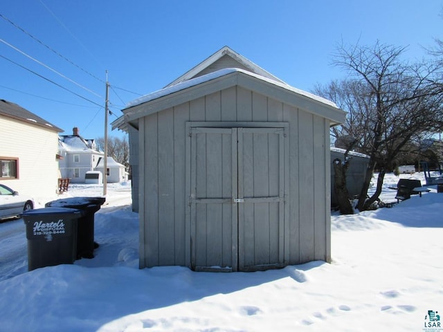 snow covered structure featuring an outdoor structure and a storage unit