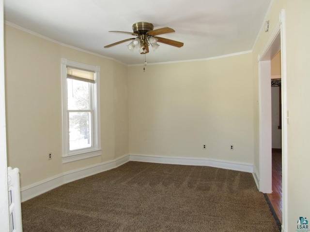 spare room with dark colored carpet, ornamental molding, and baseboards