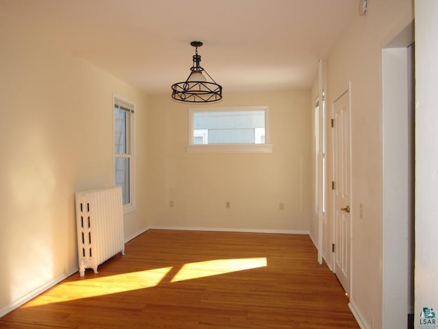 unfurnished dining area with radiator, baseboards, and wood finished floors