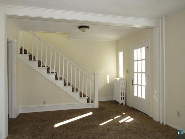 entryway featuring stairs, ornamental molding, and dark carpet