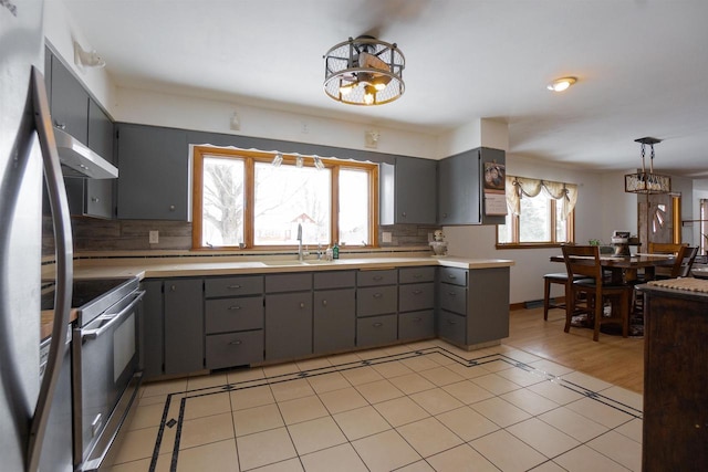 kitchen featuring stainless steel electric range oven, gray cabinets, light countertops, under cabinet range hood, and pendant lighting