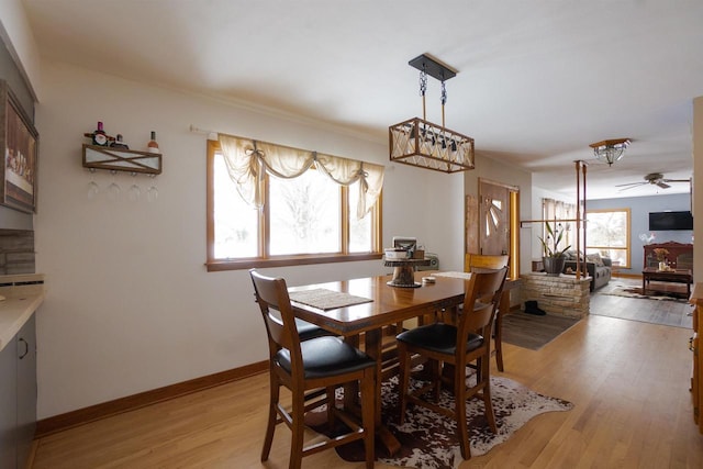 dining room with a ceiling fan, light wood-style flooring, and baseboards