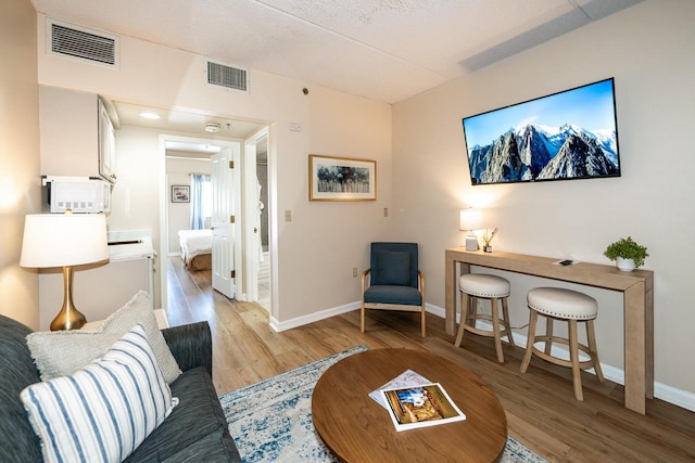 living area with baseboards, visible vents, and light wood finished floors