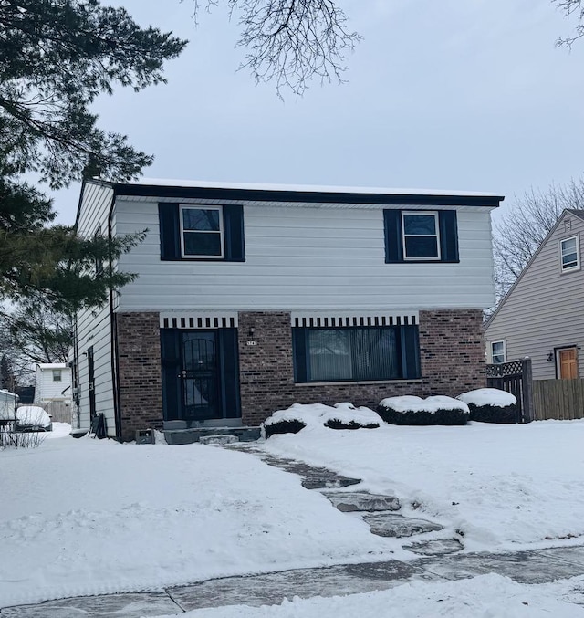 traditional home featuring a garage, brick siding, and fence