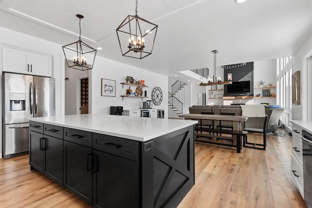 kitchen with stainless steel appliances, hanging light fixtures, light countertops, and a notable chandelier