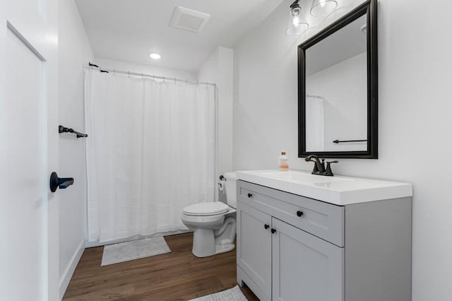 full bath with toilet, visible vents, wood finished floors, and vanity