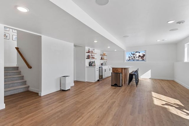 interior space with a dry bar, baseboards, stairs, light wood-type flooring, and stainless steel dishwasher