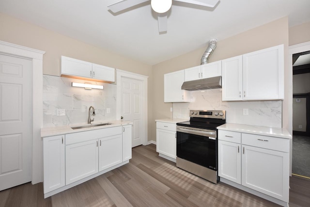 kitchen featuring light countertops, stainless steel range with electric cooktop, a sink, white cabinetry, and under cabinet range hood