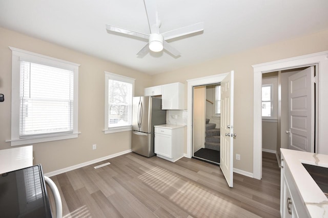 kitchen with light wood-style floors, plenty of natural light, white cabinetry, and freestanding refrigerator