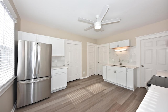 kitchen with stainless steel appliances, a wealth of natural light, light countertops, white cabinetry, and a sink