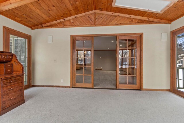 carpeted empty room with wooden ceiling, baseboards, lofted ceiling with skylight, and french doors