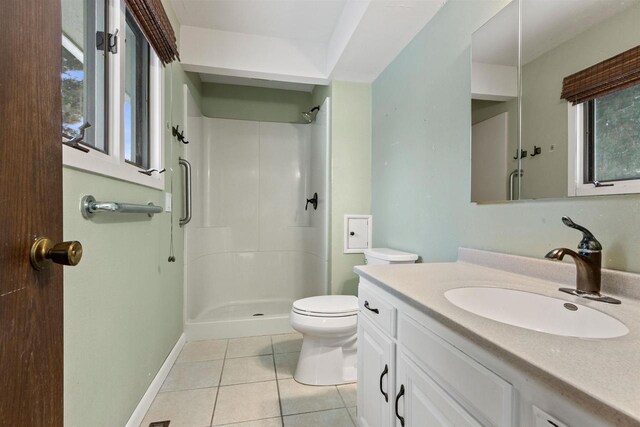 bathroom featuring toilet, a stall shower, vanity, baseboards, and tile patterned floors