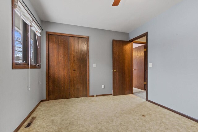 unfurnished bedroom featuring baseboards, visible vents, a closet, and light colored carpet