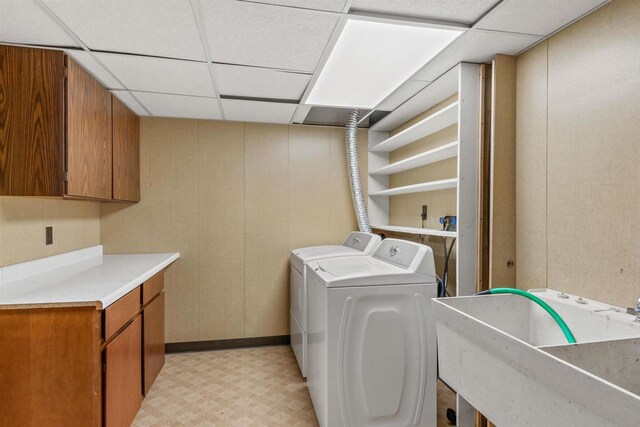 clothes washing area with light floors, cabinet space, washer and dryer, and a sink