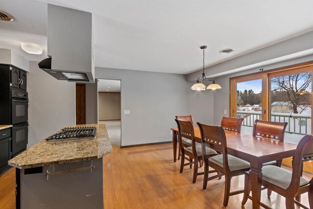 dining room featuring a chandelier, baseboards, visible vents, and light wood finished floors