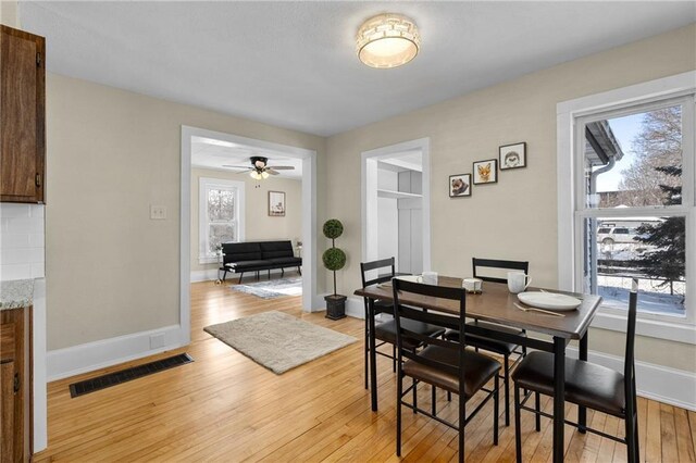 dining area featuring light wood-style floors, baseboards, visible vents, and a ceiling fan