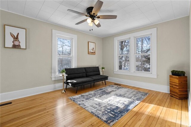 sitting room featuring ceiling fan, wood finished floors, visible vents, and baseboards