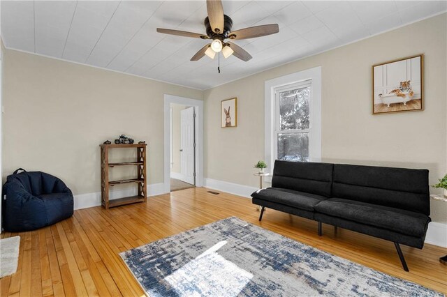 living area with ceiling fan, visible vents, baseboards, and wood finished floors