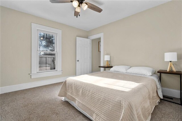 carpeted bedroom with ceiling fan and baseboards