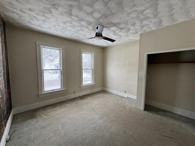 unfurnished bedroom with light carpet, ceiling fan, visible vents, and baseboards