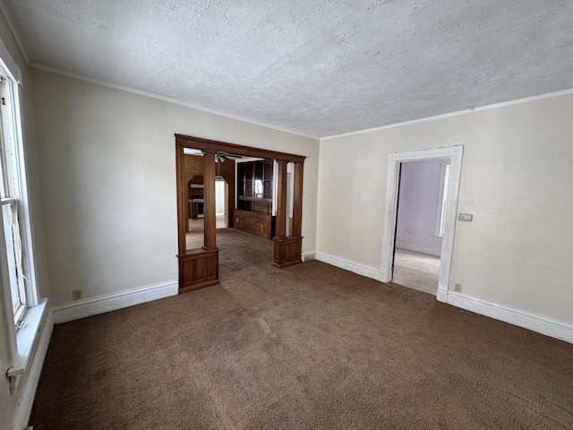 unfurnished room with baseboards, dark carpet, and crown molding