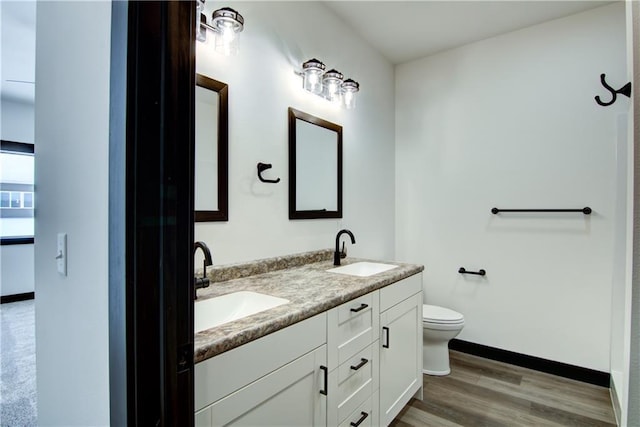 full bathroom with wood finished floors, a sink, toilet, and double vanity