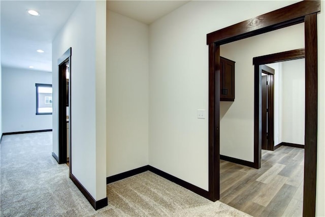 corridor with baseboards, light colored carpet, and recessed lighting