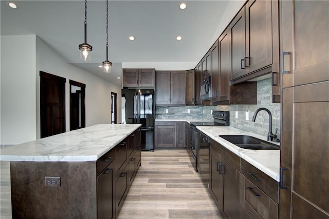 kitchen featuring a kitchen island, a sink, hanging light fixtures, light countertops, and black appliances