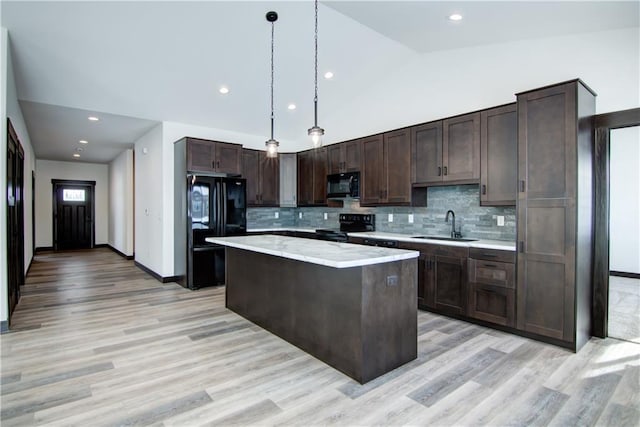 kitchen featuring dark brown cabinetry, a sink, a center island, black appliances, and pendant lighting