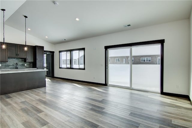 kitchen featuring tasteful backsplash, visible vents, lofted ceiling, decorative light fixtures, and light countertops