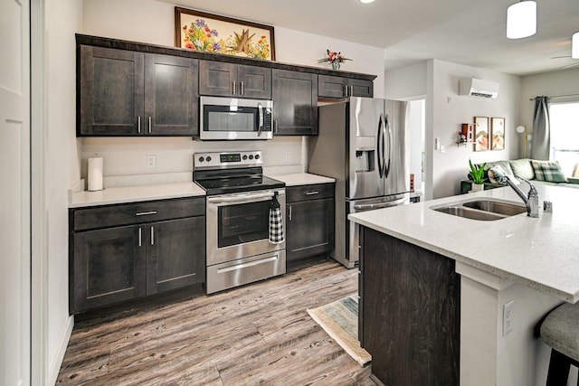 kitchen featuring stainless steel appliances, light countertops, light wood-style floors, a sink, and a wall mounted AC