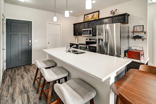 kitchen with stainless steel appliances, an island with sink, a kitchen bar, and decorative light fixtures