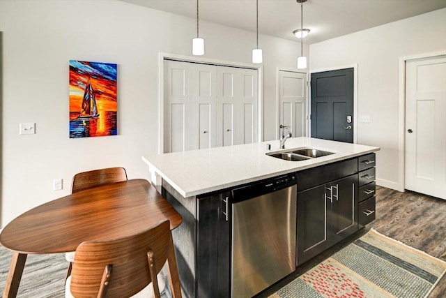 kitchen with a kitchen island with sink, a sink, light countertops, dishwasher, and pendant lighting