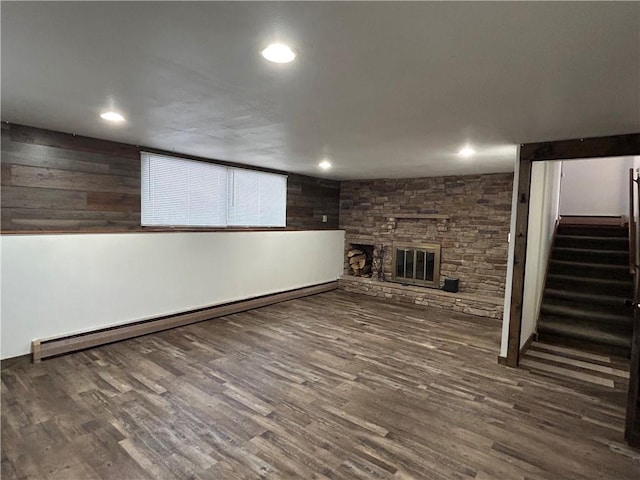 finished below grade area with baseboard heating, recessed lighting, wood finished floors, stairway, and a fireplace
