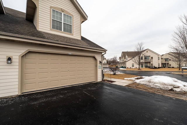 garage featuring driveway and a residential view