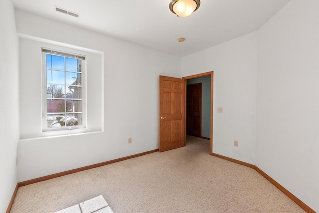 unfurnished room with carpet, visible vents, and baseboards