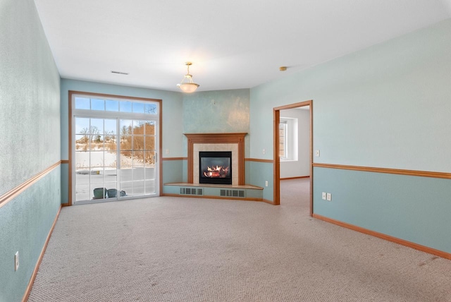 unfurnished living room with carpet floors, baseboards, visible vents, and a tile fireplace