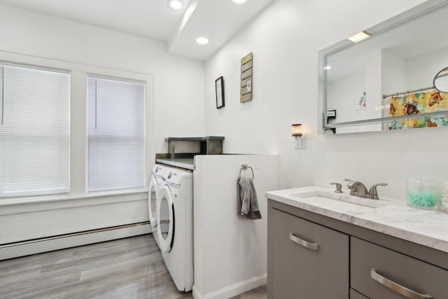 interior space featuring a baseboard radiator, recessed lighting, a sink, light wood-style floors, and independent washer and dryer