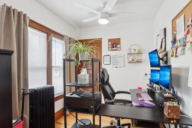 office space featuring a healthy amount of sunlight, ceiling fan, radiator heating unit, and wood finished floors