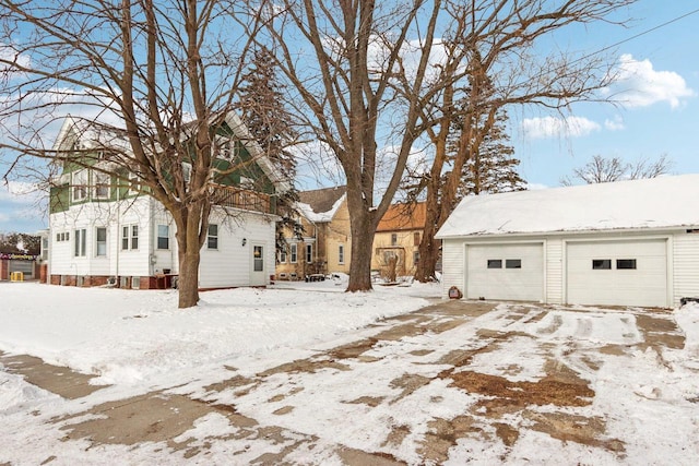 snow covered back of property featuring a detached garage