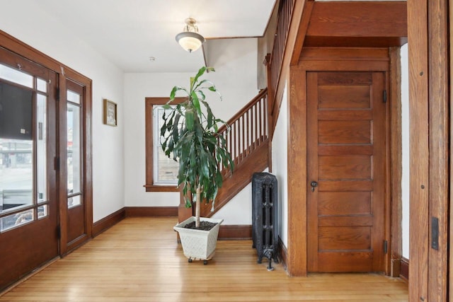 entryway featuring a healthy amount of sunlight, radiator heating unit, stairs, and light wood-style flooring