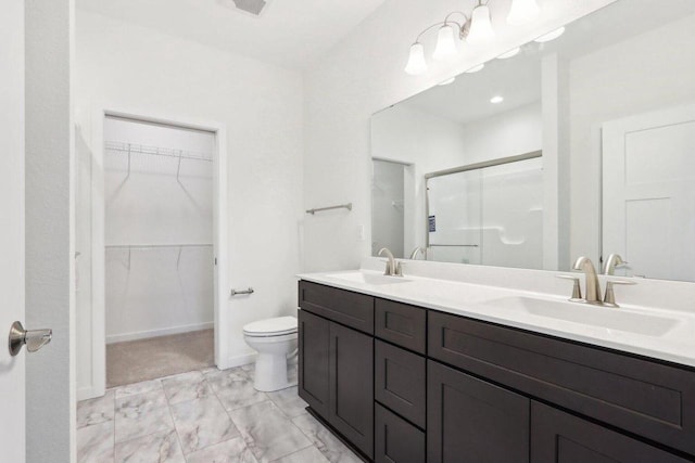 bathroom with a spacious closet, double vanity, a stall shower, and a sink