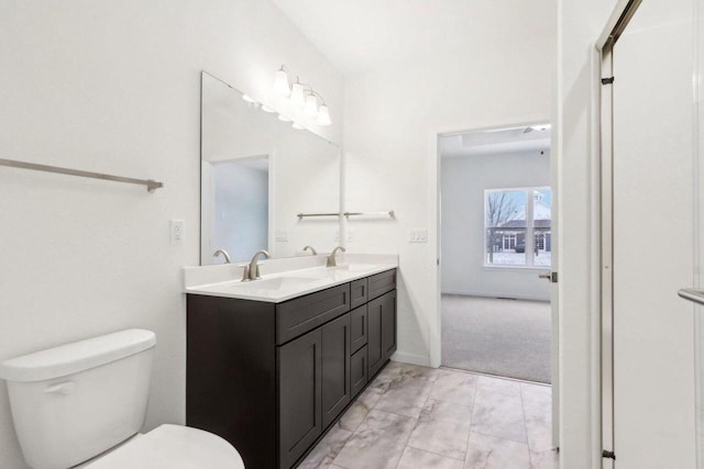 bathroom featuring baseboards, a sink, toilet, and double vanity