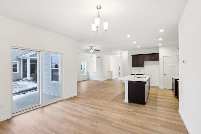 kitchen with light countertops, hanging light fixtures, light wood-style flooring, open floor plan, and a sink