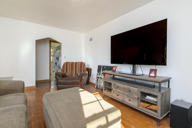 living room featuring baseboards, arched walkways, and wood finished floors