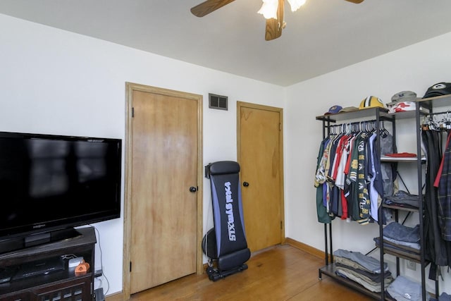 exercise room featuring visible vents, baseboards, wood finished floors, and a ceiling fan