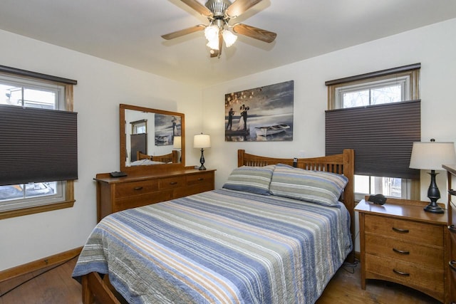 bedroom with a ceiling fan, multiple windows, wood finished floors, and baseboards